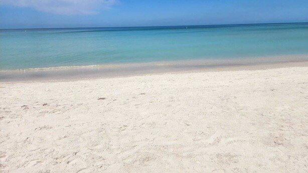 Una playa con cielo despejado y mar tranquilo.