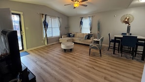 A spacious living room with a ceiling fan, a sofa, a coffee table, and a dining area with chairs and a table. - Blue Jay’s Nest
3bed/2bth, quick access to Hwy 29 (Greensboro)