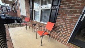 A brick building with a concrete patio, two red chairs, and a black car parked nearby. - Blue Jay’s Nest
3bed/2bth, quick access to Hwy 29 (Greensboro)