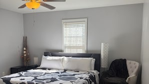 A bedroom with a bed, a chair, a standing lamp, a ceiling fan, a window with blinds, and a decorative vase. - Blue Jay’s Nest
3bed/2bth, quick access to Hwy 29 (Greensboro)