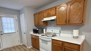 A kitchen with wooden cabinets, a white countertop, a stove, and a microwave. - Blue Jay’s Nest
3bed/2bth, quick access to Hwy 29 (Greensboro)