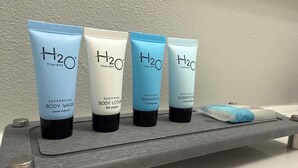 Vier H2O Therapy Körperpflegeprodukte auf einem grauen Regal.