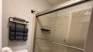Ein Badezimmer mit Toilette, einer gläsernen Duschkabine und einem Handtuchhalter.