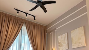Un dormitorio con cama, cortinas, ventilador de techo y decoración en la pared.