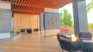Un área de estar exterior moderna con techo de listones de madera, mobiliario contemporáneo y vistas al verdor.