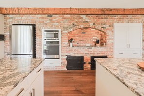 A kitchen with a brick wall, a stainless steel refrigerator, a microwave, and wooden cabinets. - Hidden Gem in the Woods: Lost Creek Lodge (Terre Haute)