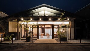 A building with a covered entrance, potted plants, and outdoor seating. - HAPPOYA (Hachinohe)