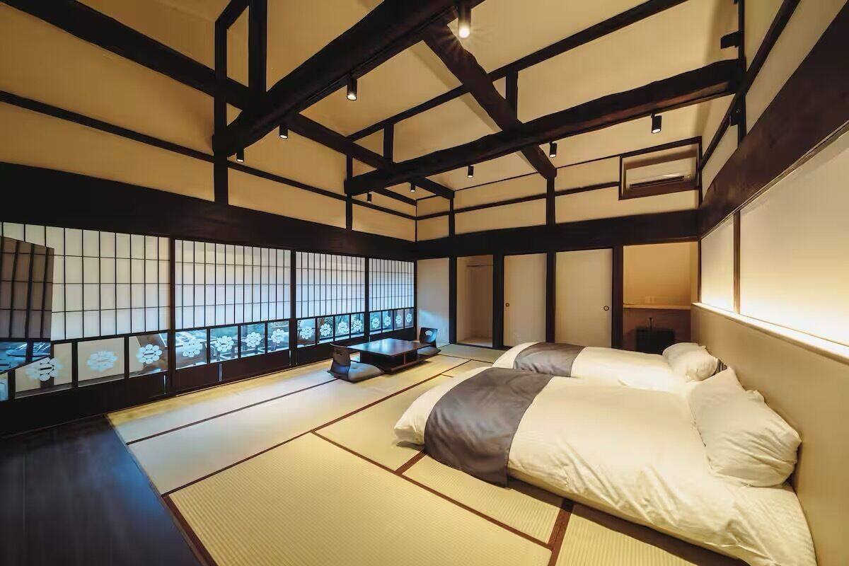 Una habitación japonesa tradicional con suelo de tatami, una cama baja y un panel shoji.