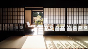 A traditional Japanese room with tatami flooring, a low table, and a chair. - HAPPOYA (Hachinohe)