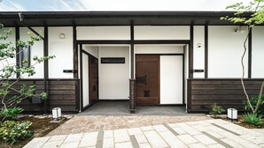 A modern building entrance with a stone pathway leading to a wooden door. - HAPPOYA (Hachinohe)