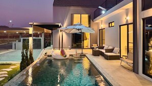 A modern house with a swimming pool, outdoor seating, and a covered patio area.