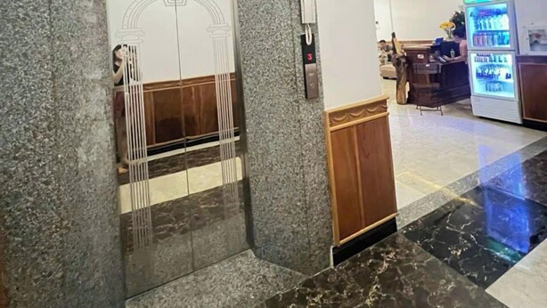 A lobby with a marble floor, a reception desk, and a vending machine.