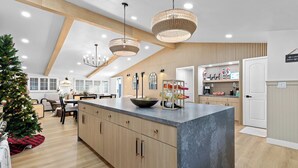 Une cuisine moderne dotée d’un grand îlot central, de meubles en bois et de luminaires suspendus.