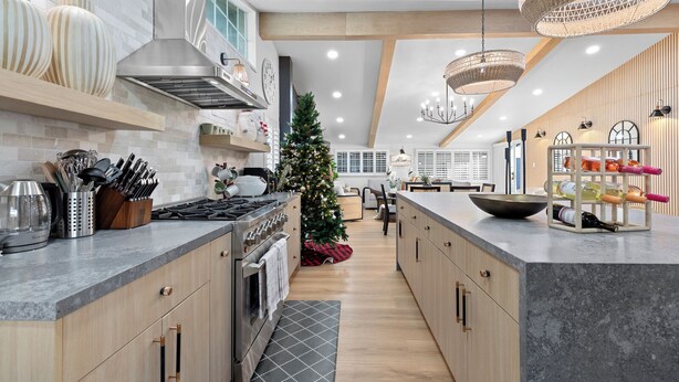 Une cuisine moderne avec un îlot central, des appareils en acier inoxydable et un sapin de Noël.