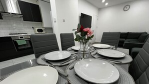 A dining area with a table set for four, including plates, cutlery, and a vase with flowers.