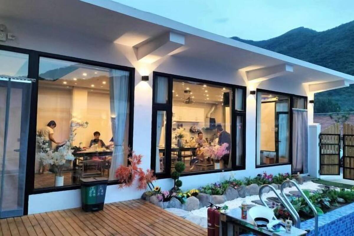 A modern building with large windows, a wooden deck, and a pool area with plants and a fire extinguisher.