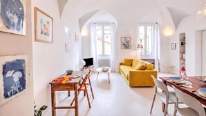 Un vaste espace de vie comprenant une table à manger, un canapé et des œuvres d’art accrochées aux murs.