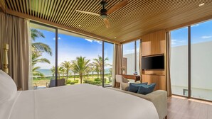 A large bed with a view of palm trees and the ocean, a TV mounted on the wall, and a wooden ceiling. - Aqua Vista Hoi An Beachfront Villas (Da Nang)