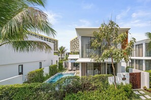A modern residential building with a swimming pool, lush greenery, and a clear sky. - Aqua Vista Hoi An Beachfront Villas (Da Nang)
