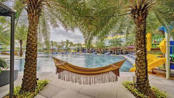 A pool area with a hammock, palm trees, and a children's play area.