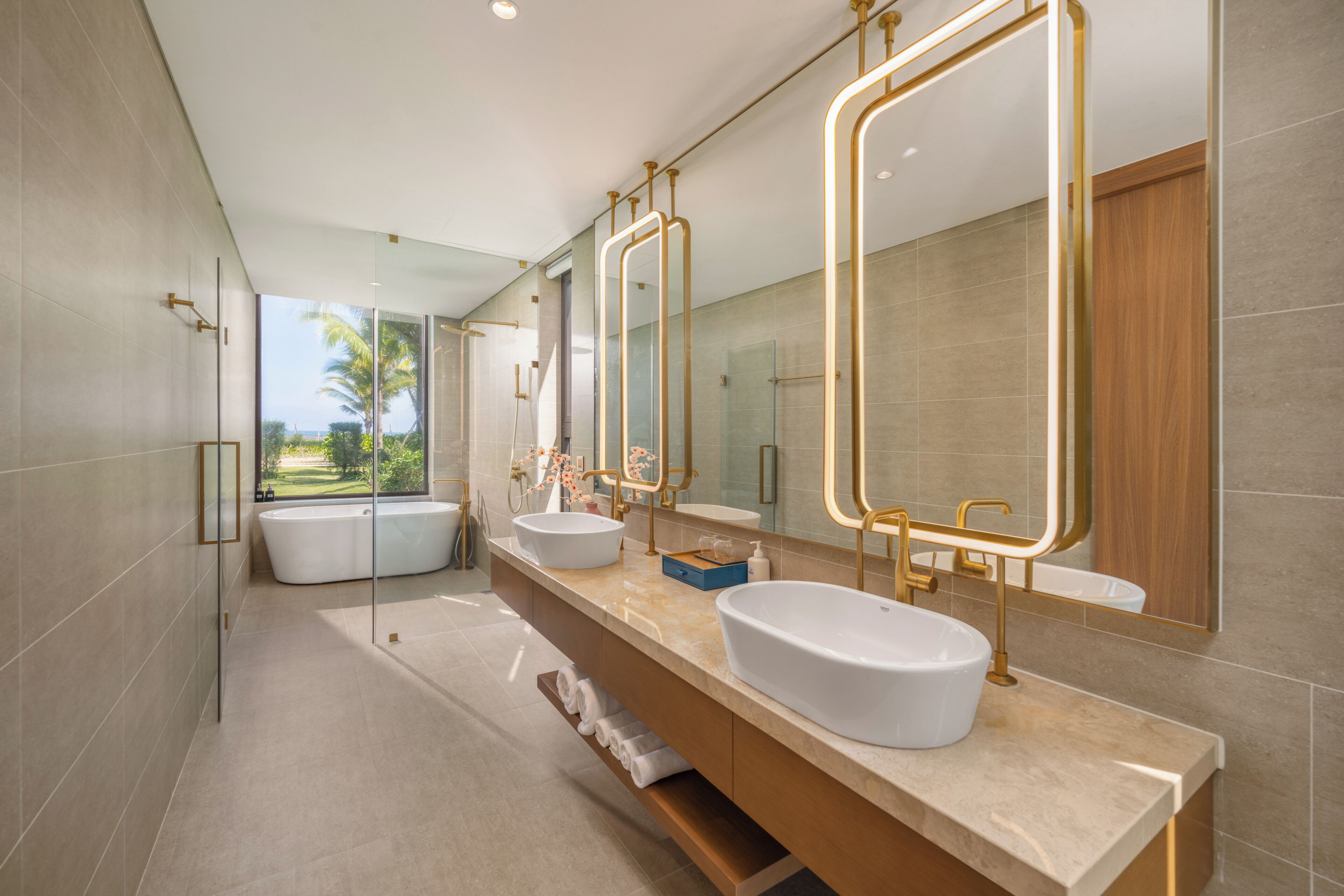 Un baño moderno con dos lavamanos, una bañera y espejos grandes.