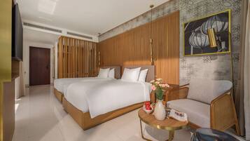 A modern hotel room with a large bed, a sofa, a small table with a vase of flowers, and a painting on the wall.