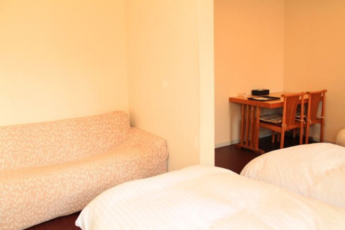 Une pièce comprenant un canapé, un petit bureau avec une chaise et deux lits.