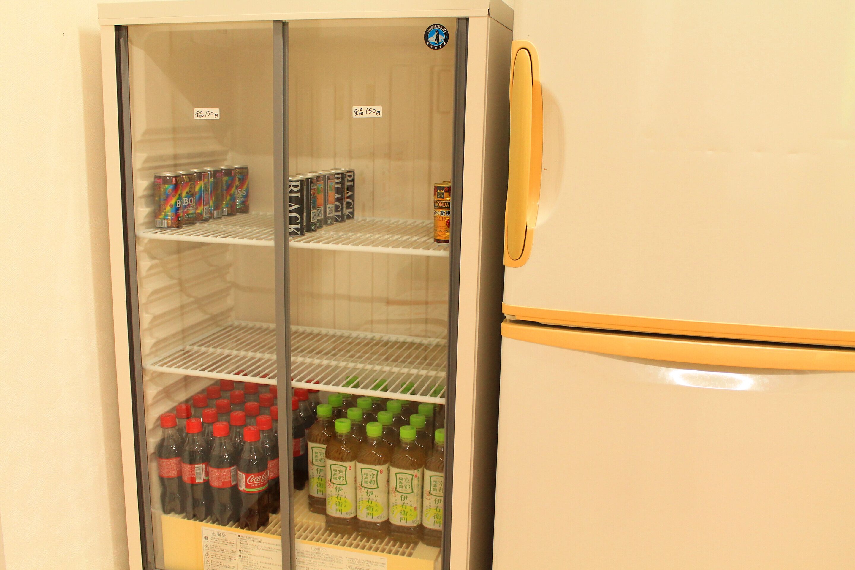 A refrigerator with multiple shelves containing beverages and canned drinks.