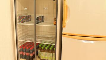 A refrigerator with multiple shelves containing beverages and canned drinks.