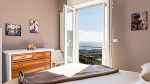 A bedroom with a large bed, a dresser, and a view of a bridge through an open door. - Casa della Nonna Gilda by Interhome (Sanremo)