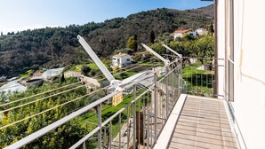 A balcony with a view of a hillside, a greenhouse, and a white building with a red roof. - Casa della Nonna Gilda by Interhome (Sanremo)