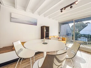 A modern dining area with a round table, white chairs, and a sofa with a cushion. - Phare de Kernevest by Interhome (Saint Philibert)