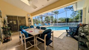 An outdoor pool area with a table and chairs, a ceiling fan, and a view of the pool. - Josiane's Chic Oasis (Davenport)