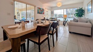 A dining area with a wooden table, chairs, and a sofa in the background. - Josiane's Chic Oasis (Davenport)