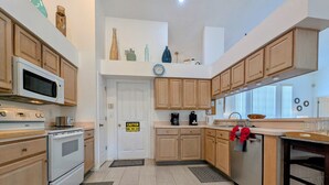 A modern kitchen with wooden cabinets, a microwave, stove, and a coffee maker. - Josiane's Chic Oasis (Davenport)