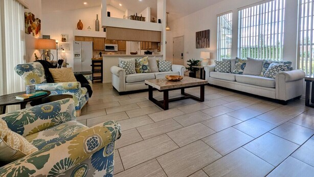 A spacious living room with a high ceiling, a ceiling fan, and a kitchen in the background. - Josiane's Chic Oasis (Davenport)