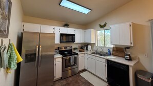 A modern kitchen with white cabinets, stainless steel appliances, a microwave, oven, and a dishwasher.