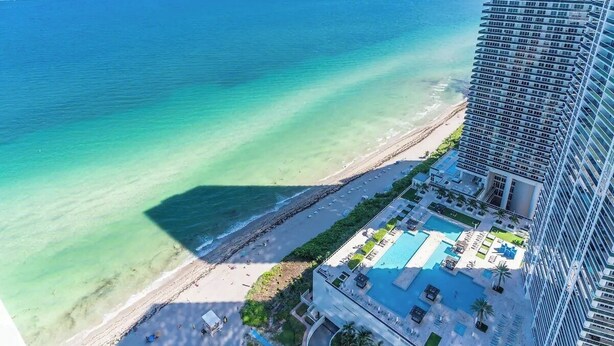 Un hotel de gran altura con zona de piscina, playa y vistas al océano.