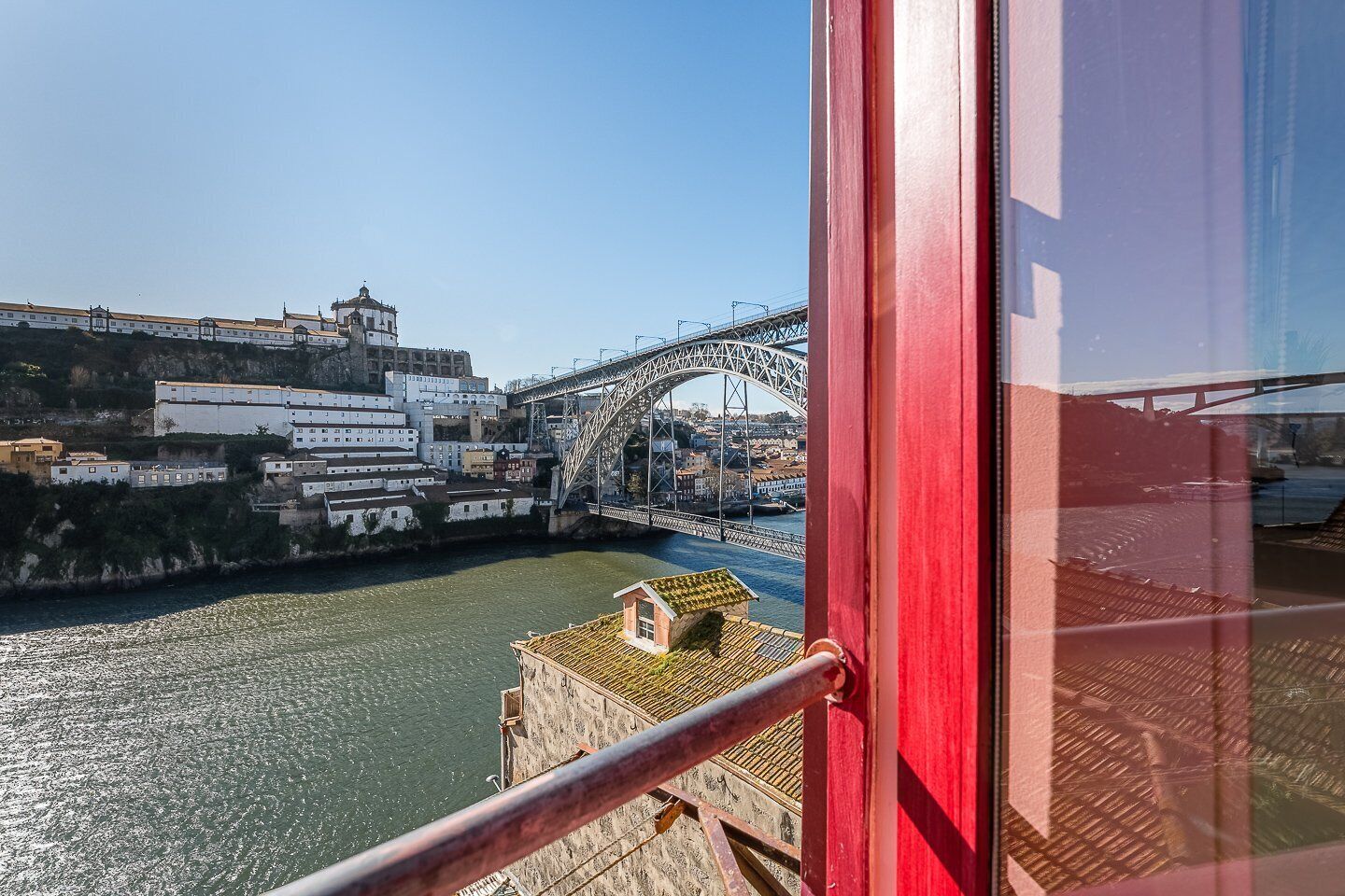 Vista desde una ventana sobre un río con un puente y edificios al fondo.