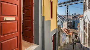 Eine enge Straße mit einer roten Tür, einem gelben Gebäude und einer Brücke im Hintergrund.