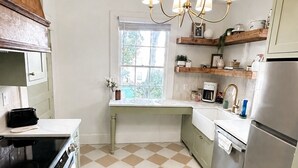 Una cocina con piso de cuadros, estufa, refrigerador y ventana con vista a follaje.