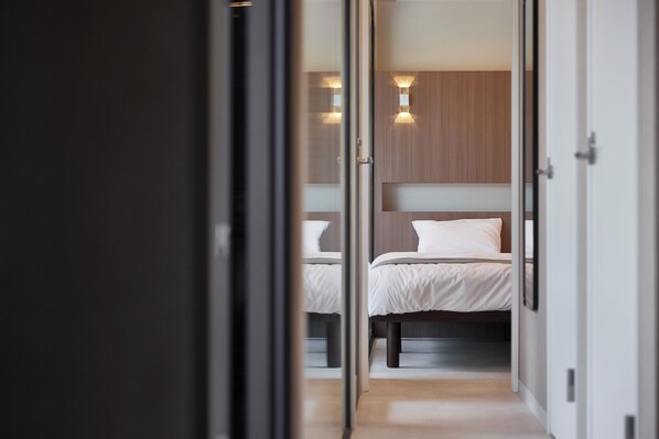 A hotel room with two beds, a wooden headboard, and wall-mounted lighting. - IZA GLAMPING Chihaya-Akasaka Village (Chihayaakasaka-mura)