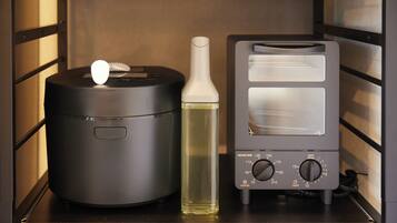 A kitchen with a rice cooker, a bottle of cooking oil, and a toaster.