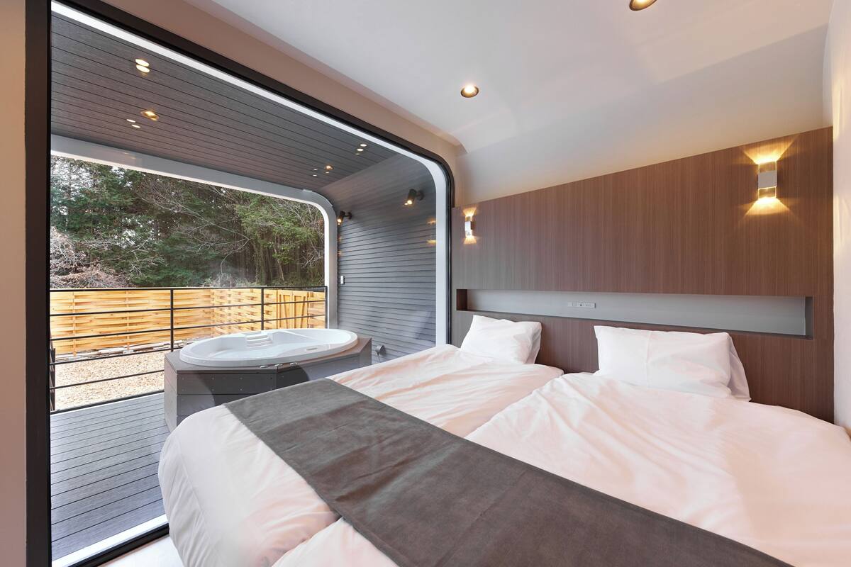 Un dormitorio moderno con una cama grande, un ventanal integrado y un jacuzzi.