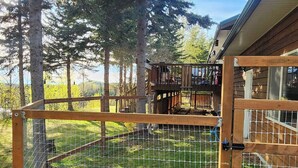 Ein eingezäunter Außenbereich mit einer Holzterrasse und einem Gebäude im Hintergrund.