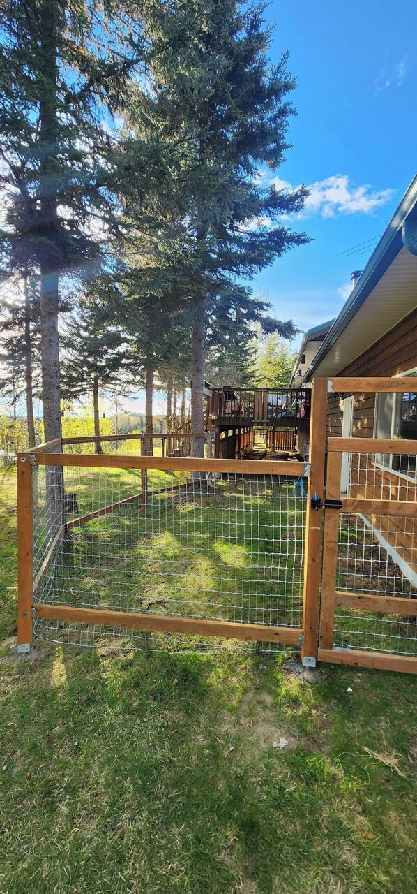 A fenced outdoor area with a wooden deck and a building in the background.