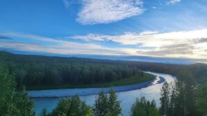 Ein Fluss schlängelt sich durch ein bewaldetes Tal unter einem wolkenlosen Himmel.