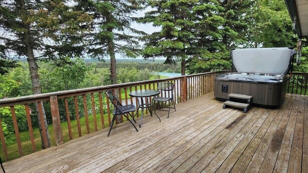 Eine Holzterrasse mit Whirlpool, Tisch und zwei Stühlen.
