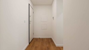 A narrow hallway with white walls and wooden flooring.