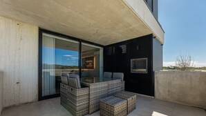 A modern outdoor seating area with wicker furniture and a glass door leading to a room.